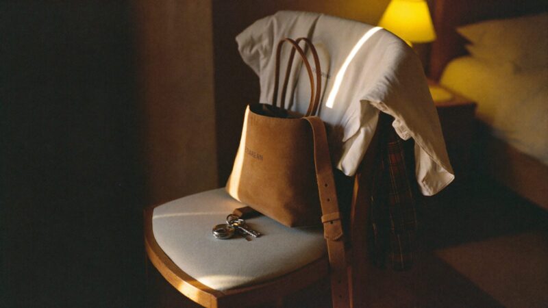 Clothes laid out neatly on a chair the night before a big day, with a watch and keys on the seat, warm bedside lamp light